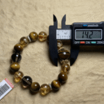 Close-up of a smoky quartz bracelet with deep brown translucent crystals, set against a watery blue background to emphasize the water element.