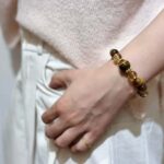 A person wearing a citrine bracelet on their wrist, showcasing its elegant fit and earthy tones in a natural setting.
