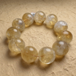 A single strand of 20.5mm natural Citrine bracelet resting on dark wood grain, showcasing its warm clarity.