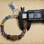 Three crystal bracelets layered on wrist showing amethyst, aquamarine and gold rutilated quartz in natural light