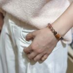 Artistic flat lay of eleven crystal bracelets including amethyst, aquamarine, strawberry quartz and ghost crystals, arranged in five elements pattern