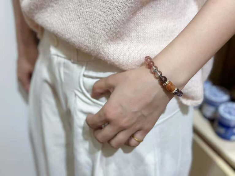 Artistic flat lay of eleven crystal bracelets including amethyst, aquamarine, strawberry quartz and ghost crystals, arranged in five elements pattern