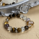 Smoky quartz bracelet resting near a water feature, with deep brown crystals set against a flowing blue background to highlight the water element.