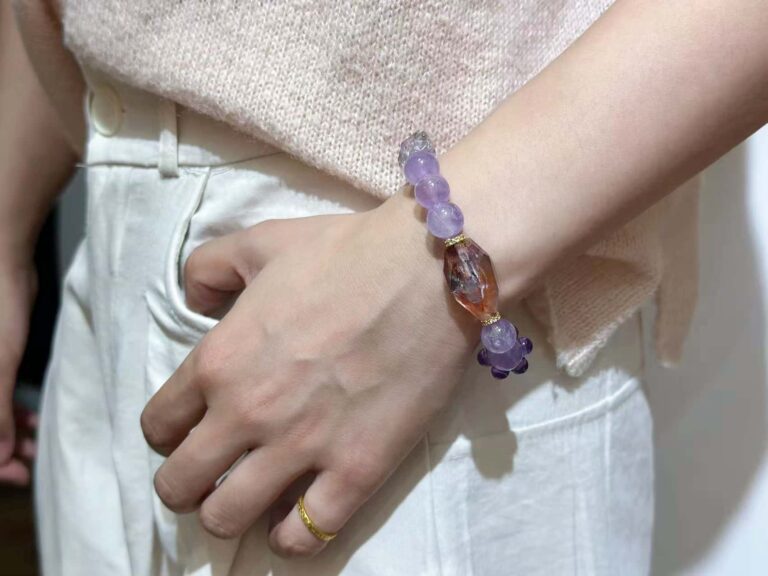 Super seven crystal bracelet with purple hue and metallic flashes, displayed on geometric background