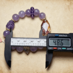 Red phantom quartz bracelet with flower-like inclusions, captured with dramatic lighting