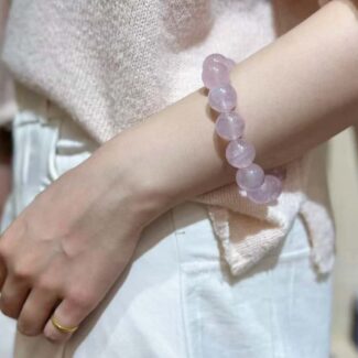 Rose quartz bracelet elegantly worn on wrist, showcasing how light passes through the pink crystals in natural setting
