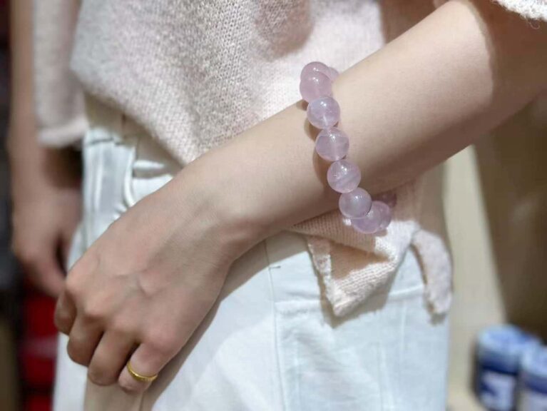Rose quartz bracelet elegantly worn on wrist, showcasing how light passes through the pink crystals in natural setting